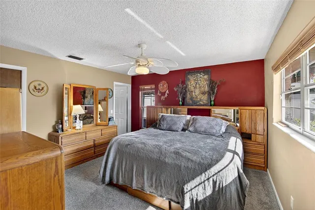 a bedroom with a bed a dresser and potted plants with wooden floor
