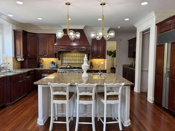 a kitchen with stainless steel appliances kitchen island granite countertop wooden floors refrigerator and cabinets
