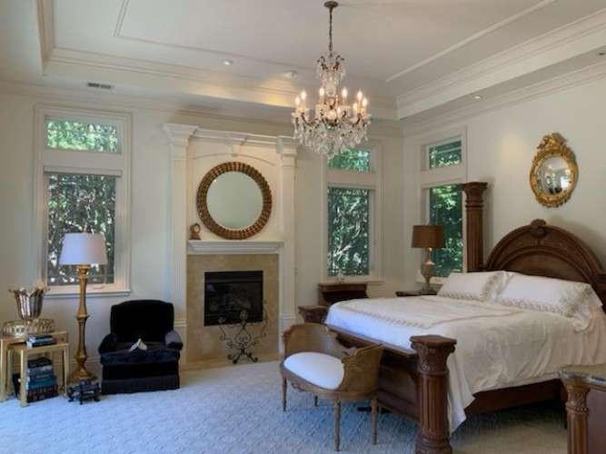 5403 Blackhawk Drive Danville, CA 94506 - Photo 20 of 47 a bedroom with a bed a fireplace and a chandelier