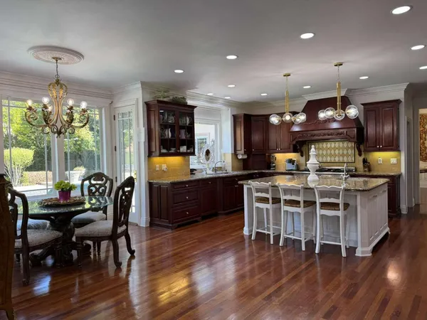 a kitchen with stainless steel appliances granite countertop a stove top oven a sink dishwasher a dining table and chairs with wooden floor