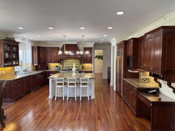 a kitchen with stainless steel appliances granite countertop a stove a refrigerator a kitchen island a dining table and chairs with wooden floor