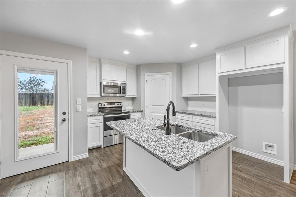 228 St Charles Drive, Unit B Springtown, TX 76082 - Photo 3 of 20 a kitchen with granite countertop kitchen island a sink appliances and cabinets