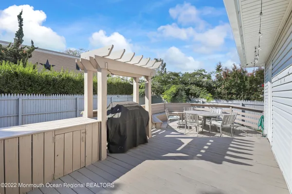 a view of a patio with table and chairs with wooden floor and fence