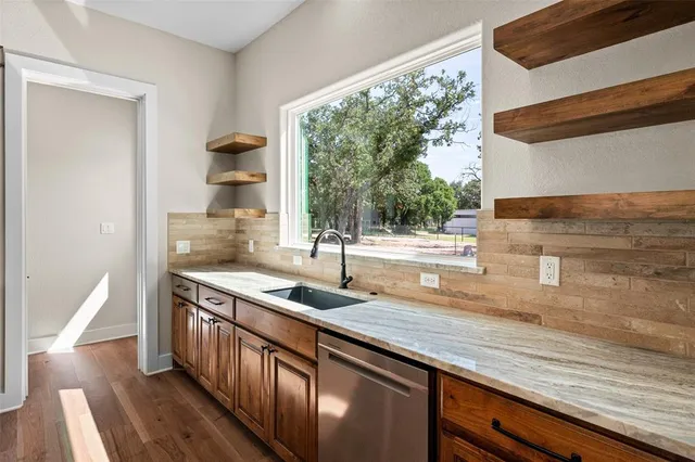a kitchen with stainless steel appliances granite countertop a sink a stove and a wooden floors
