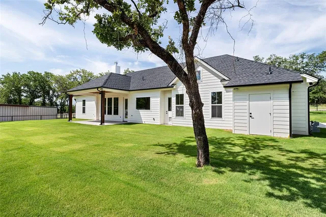 a view of a house with a big yard and large trees