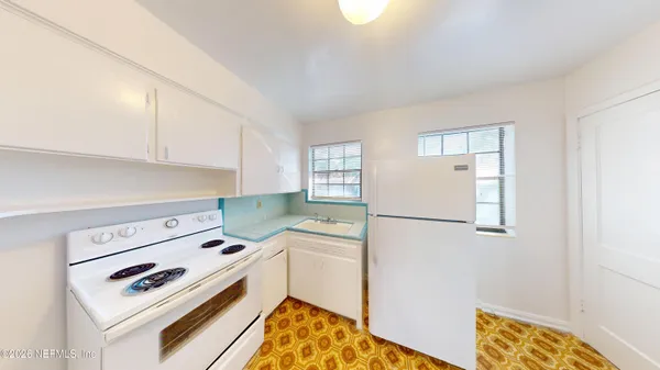 a kitchen with a refrigerator a stove and white cabinets