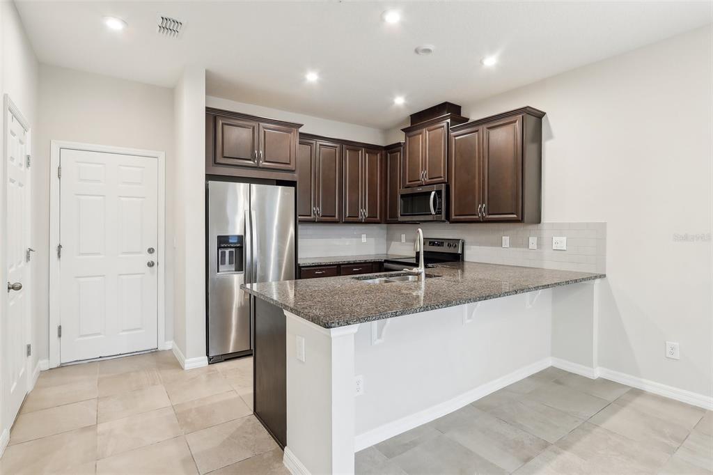9457 Randal Park Boulevard Orlando, FL 32832 - Photo 13 of 52 a kitchen with stainless steel appliances granite countertop a sink refrigerator and cabinets