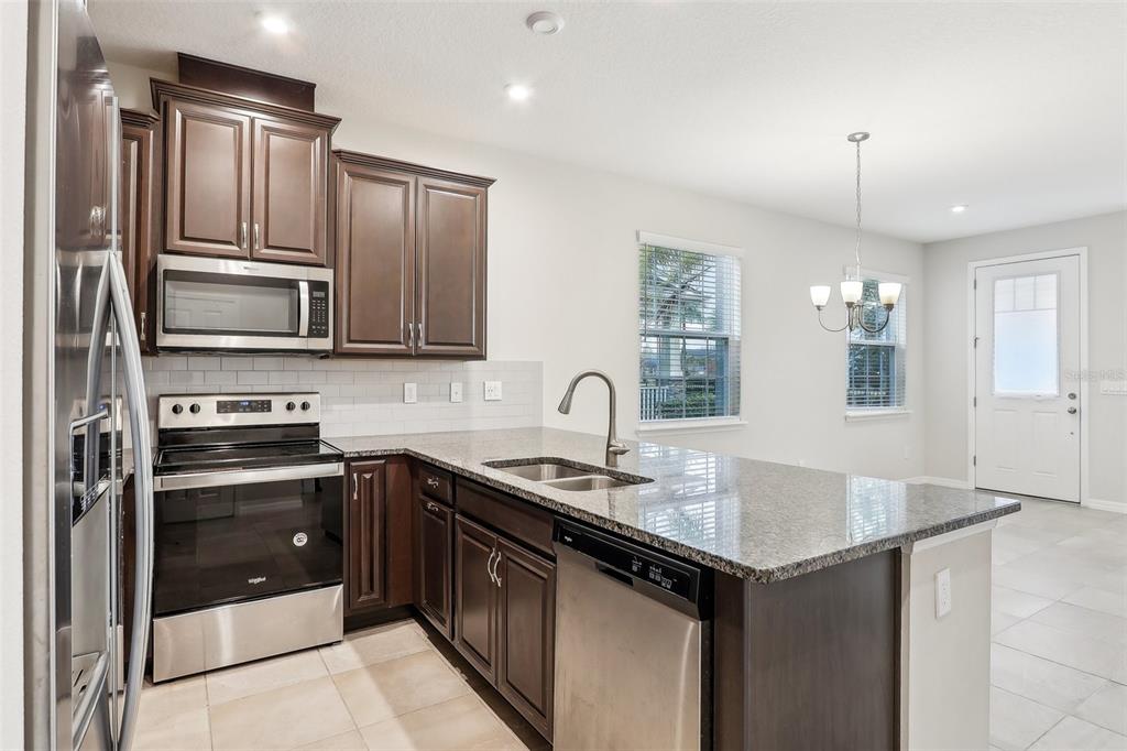 9457 Randal Park Boulevard Orlando, FL 32832 - Photo 14 of 52 a kitchen with kitchen island granite countertop a sink stove and refrigerator