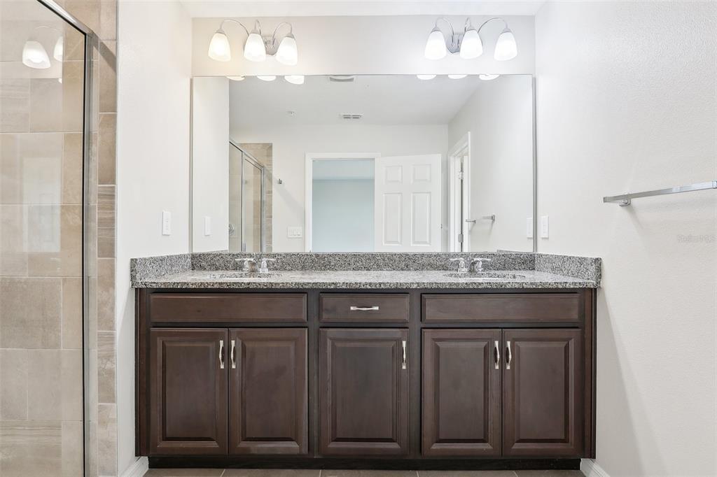 9457 Randal Park Boulevard Orlando, FL 32832 - Photo 32 of 52 a bathroom with a granite countertop sink a large mirror and a vanity