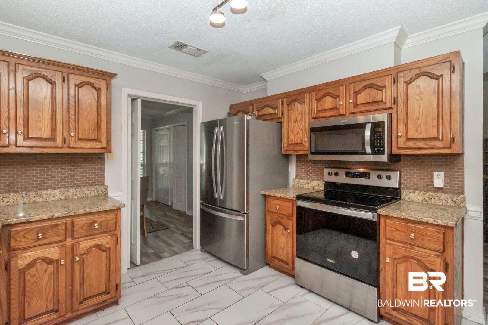 9991 Wedgefield Court Mobile, AL 36608 - Photo 9 of 30 Kitchen featuring light tile patterned floors, decorative backsplash, crown molding, and stainless steel appliances