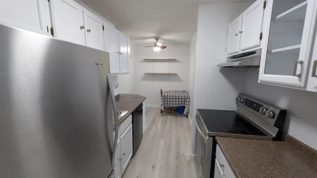 a kitchen with stainless steel appliances granite countertop a refrigerator a stove and a sink with wooden floor