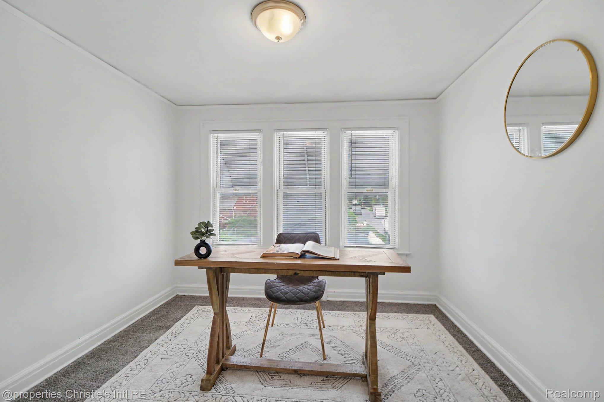 18315 Prairie Street Detroit, MI 48221 - Photo 8 of 16 Bright room featuring three windows with blinds, a ceiling-mounted light fixture, white walls, and dark carpeting
