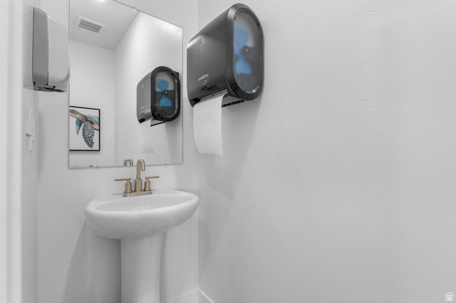 1418 West 2350th South, Unit 15 Perry, UT 84302 - Photo 10 of 22 Pedestal sink with a brushed nickel faucet and a wall-mounted mirror
