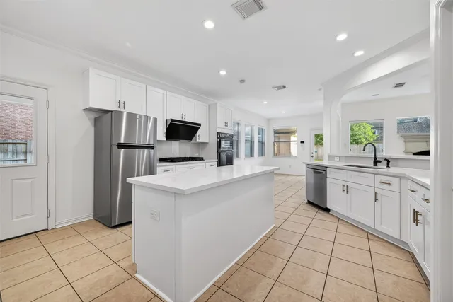 a large kitchen with a refrigerator a stove a sink a washer dryer and a dining table