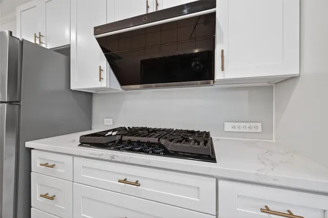a kitchen with stainless steel appliances granite countertop white cabinets and a stove