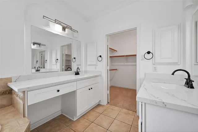 a spacious bathroom with a double vanity sink mirror and bathtub