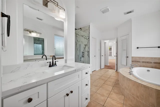 a spacious bathroom with a tub sink and mirror