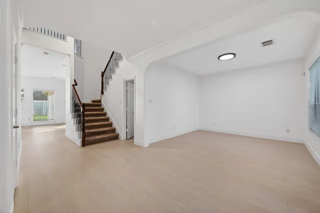a view of an empty room with stairs and a window