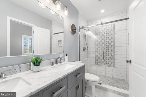 a bathroom with a granite countertop sink a toilet and shower