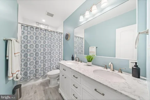 a bathroom with a granite countertop double vanity sink mirror and toilet