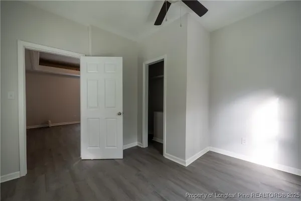 an empty room with wooden floor closet and windows