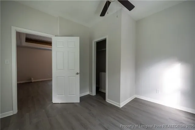 an empty room with wooden floor closet and windows