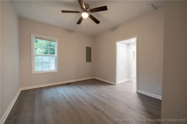 an empty room with wooden floor ceiling fan and windows