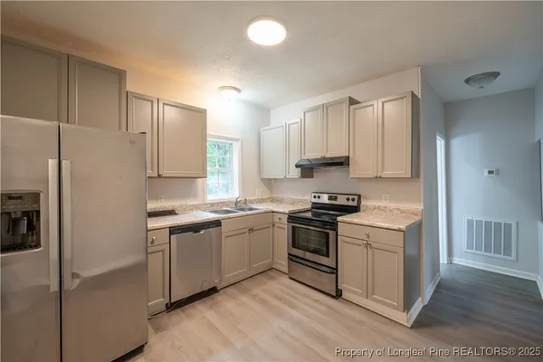 a kitchen with stainless steel appliances granite countertop a stove a sink and a refrigerator