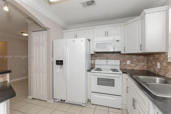 a kitchen with white cabinets and white appliances