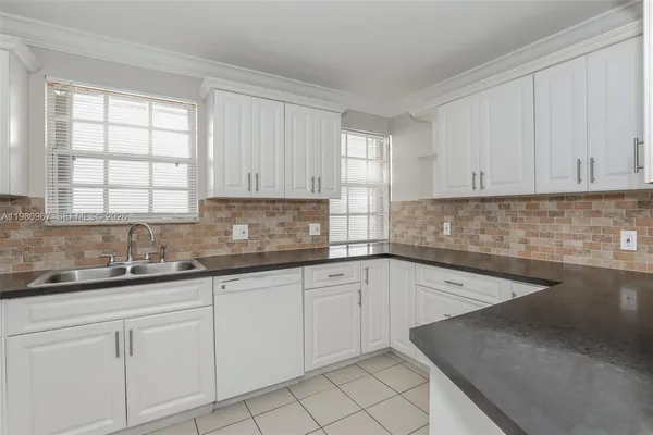a kitchen with granite countertop white cabinets and sink