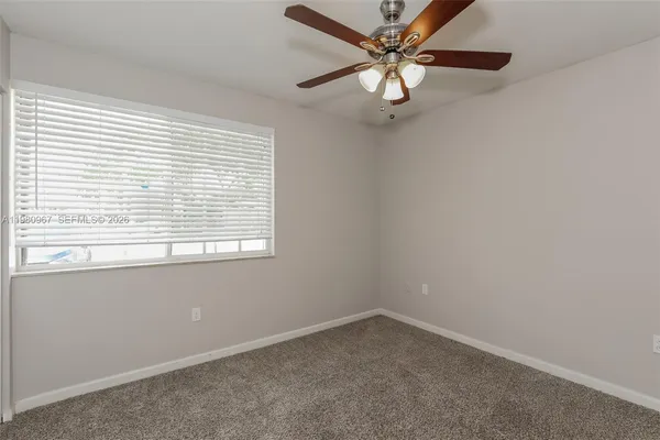 an empty room with a window and a fan