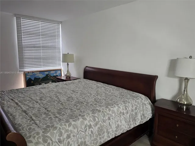 a bedroom with a bed and a lamp on dresser