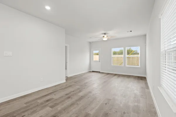 an empty room with wooden floor and windows