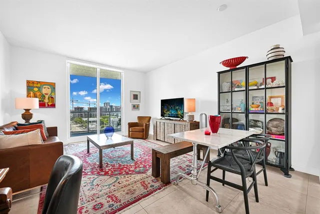 a living room with furniture a flat screen tv and a floor to ceiling window