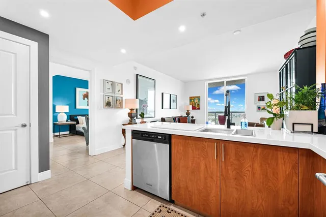 a kitchen with stainless steel appliances granite countertop a sink counter space and a view of living room
