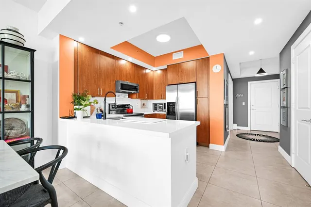 a kitchen with stainless steel appliances a refrigerator a stove a sink dishwasher and a dining table with the kitchen view