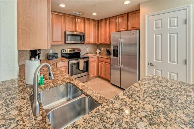 a kitchen with granite countertop a refrigerator and a stove top oven