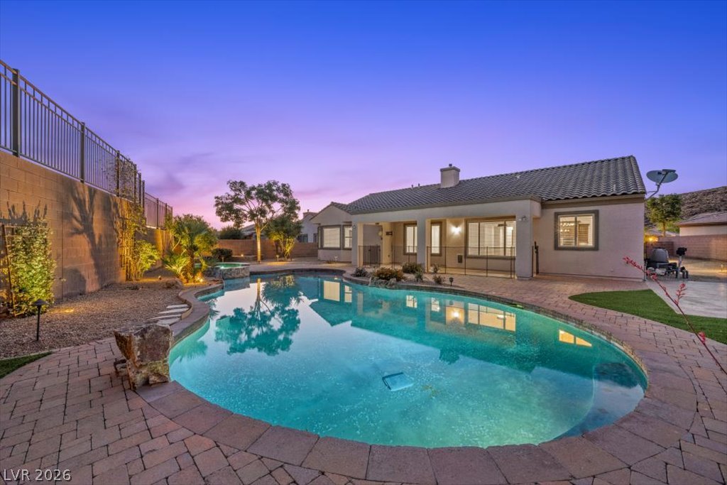 2125 De Rouge Avenue Henderson, NV 89044 - Photo 13 of 96 An inviting pool shimmers under a twilight sky, perfectly complementing the elegant home.