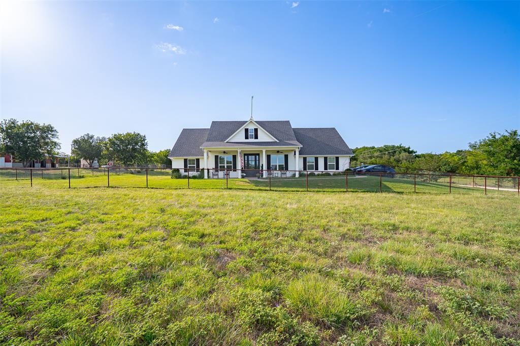 1920 Meander Road Granbury, TX 76049 - Photo 3 of 40 Single-story residence featuring a white exterior, dark gabled roof, and a covered front porch with white columns