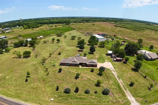 a view of a house with a big yard and a large tree