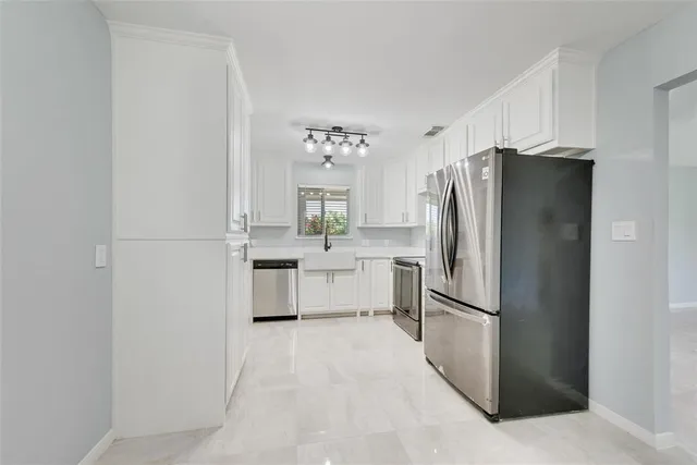a kitchen with white cabinets and stainless steel appliances