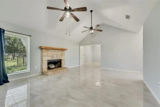 a view of an empty room with a fireplace and a window