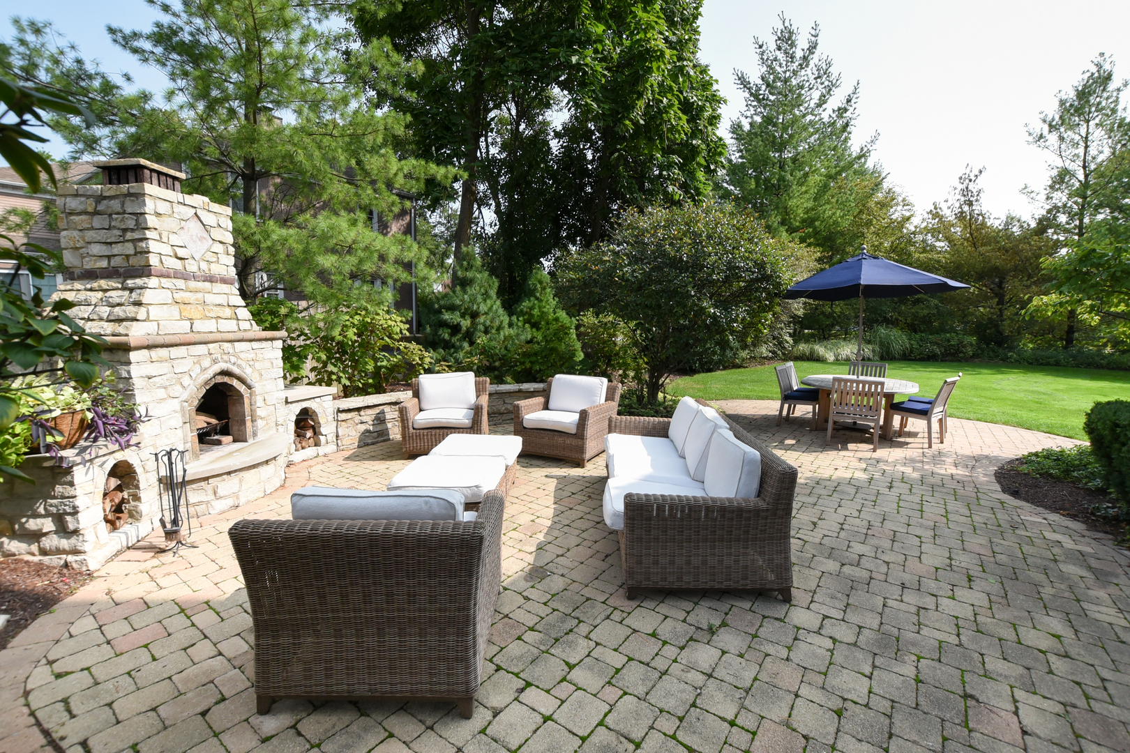 300 North Delaplaine Road Riverside, IL 60546 - Photo 47 of 50 a view of a patio with a dining table and chairs under an umbrella with large trees