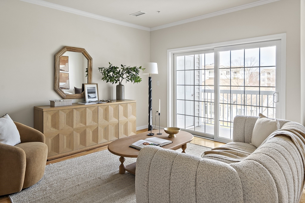 107 Clocktower Drive, Unit 303 Waltham, MA 02452 - Photo 2 of 18 a bedroom with a bed a couch and dresser with wooden floor