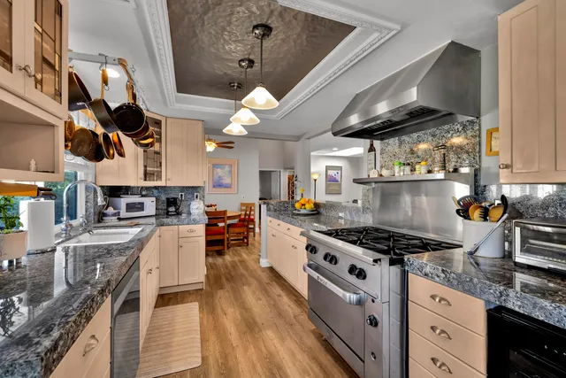 a kitchen with stainless steel appliances granite countertop a stove a sink dishwasher and cabinets with wooden floor