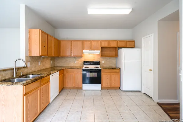 a kitchen with stainless steel appliances granite countertop a refrigerator and a stove top oven
