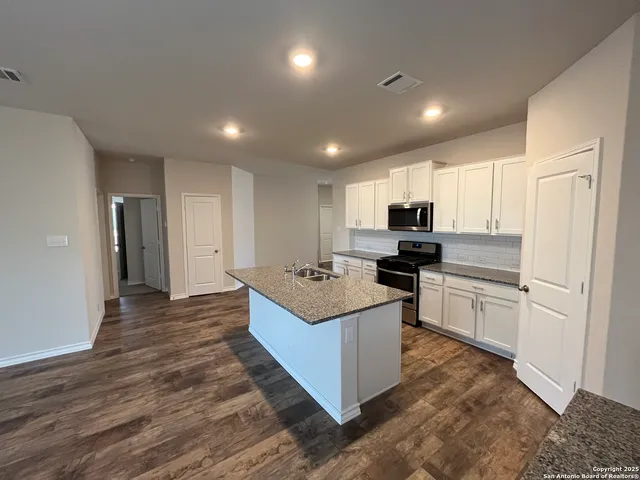 a kitchen with kitchen island stainless steel appliances sink stove microwave and cabinets
