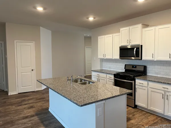 a kitchen with granite countertop a stove and a sink