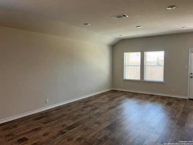 a view of an empty room with wooden floor and window