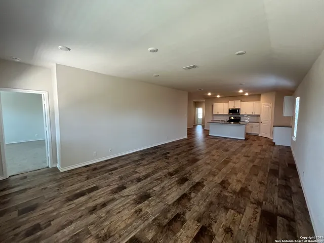 a view of a big room with wooden floor and a kitchen